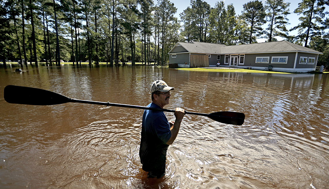 The home of Kenny Babb is surrounded by water as he retrieves a paddle that floated away while the Little River continues to rise in the aftermath of Hurricane Florence in Linden, N.C., Tuesday, Sept. 18, 2018